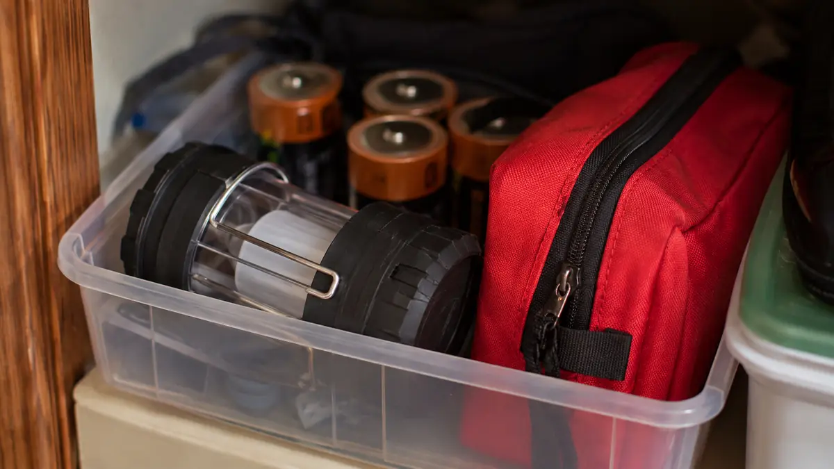 Collapsible LED lantern packed in a plastic storage bin with other emergency supplies in a hall closet